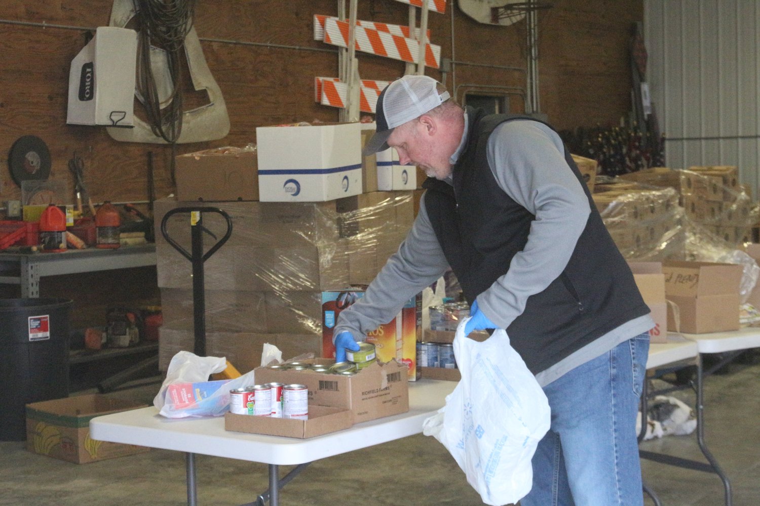 Kalona City Administrator Ryan Schlabaugh prepares bags of groceries at the city’s pop-up food pantry at the city shop on Saturday morning.